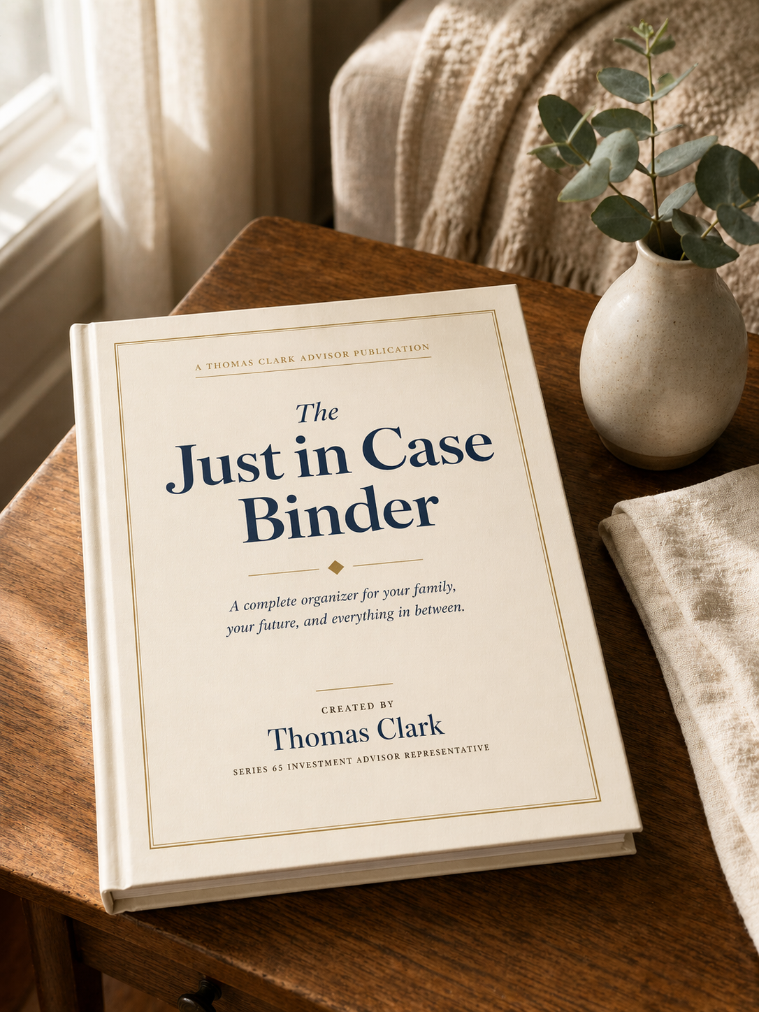 The Just in Case Binder, a sage-green hardcover organizer, resting on a warm wood side table with a small eucalyptus sprig and linen throw, in soft morning light.